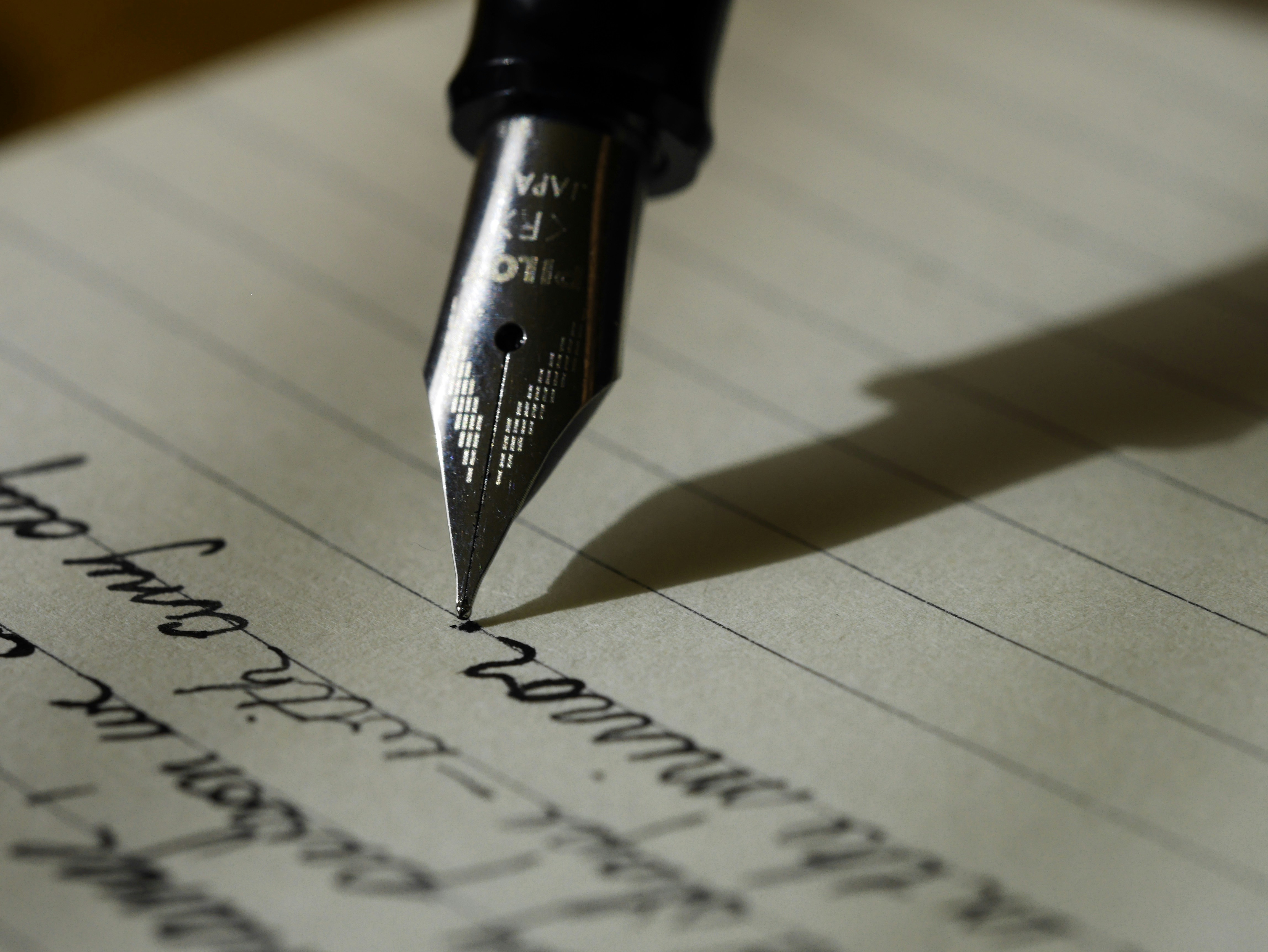 A fountain pen writes on lined paper.